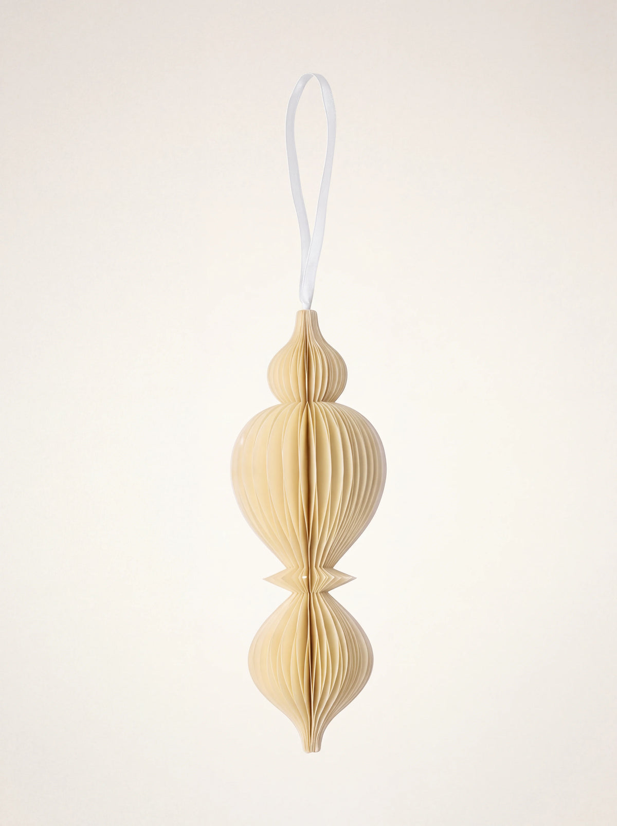 Cream paper honeycomb ornament with a tiered spire silhouette and hanging ribbon loop
