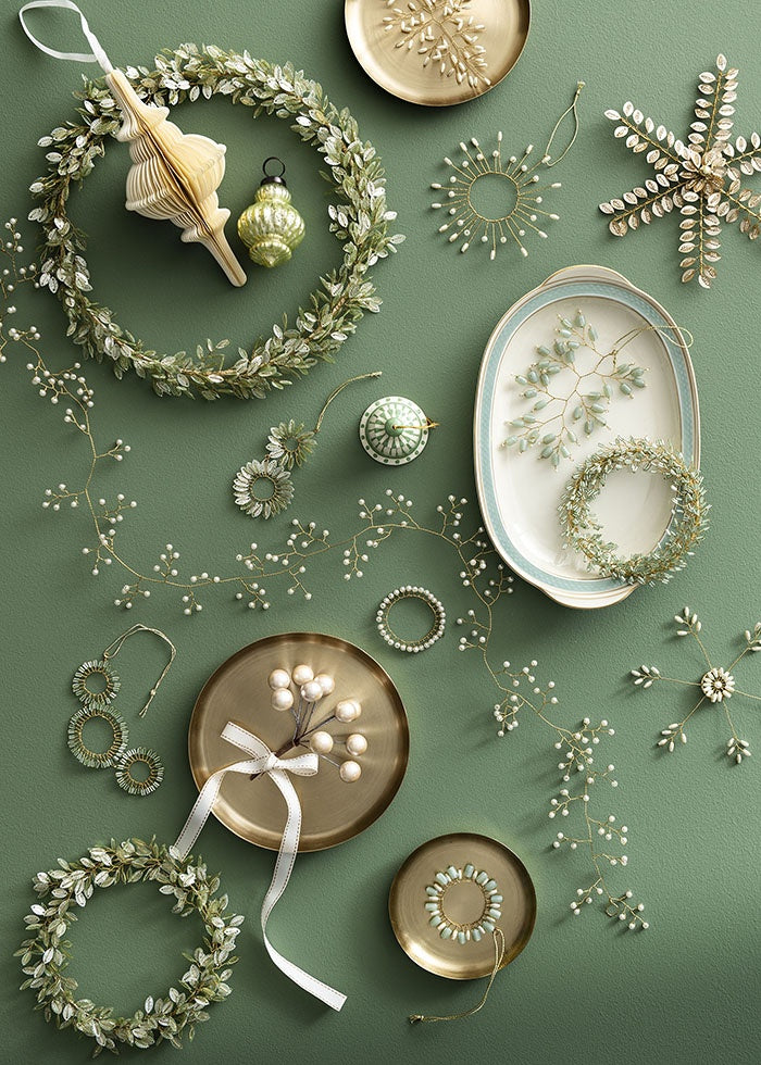 Cream paper spire ornament shown in a festive flat-lay arrangement inside a beaded leaf wreath