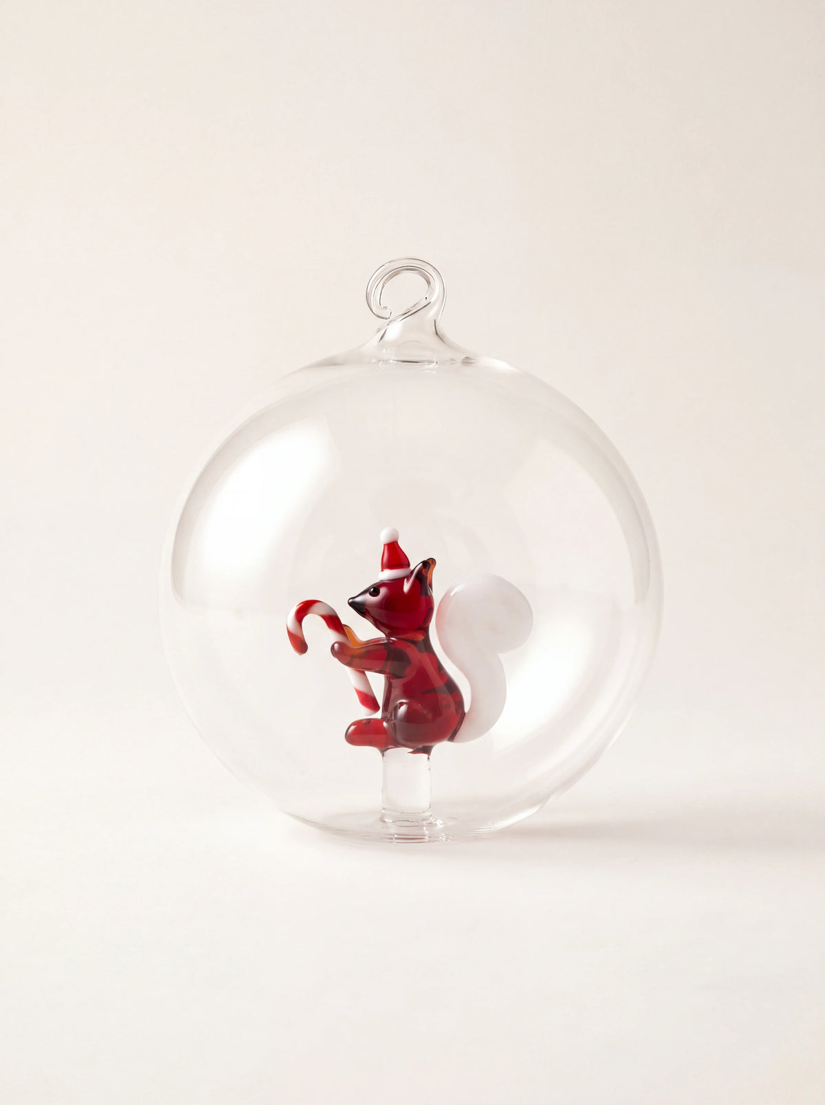 Clear borosilicate glass bauble enclosing a small glass squirrel in a Santa hat holding a candy cane