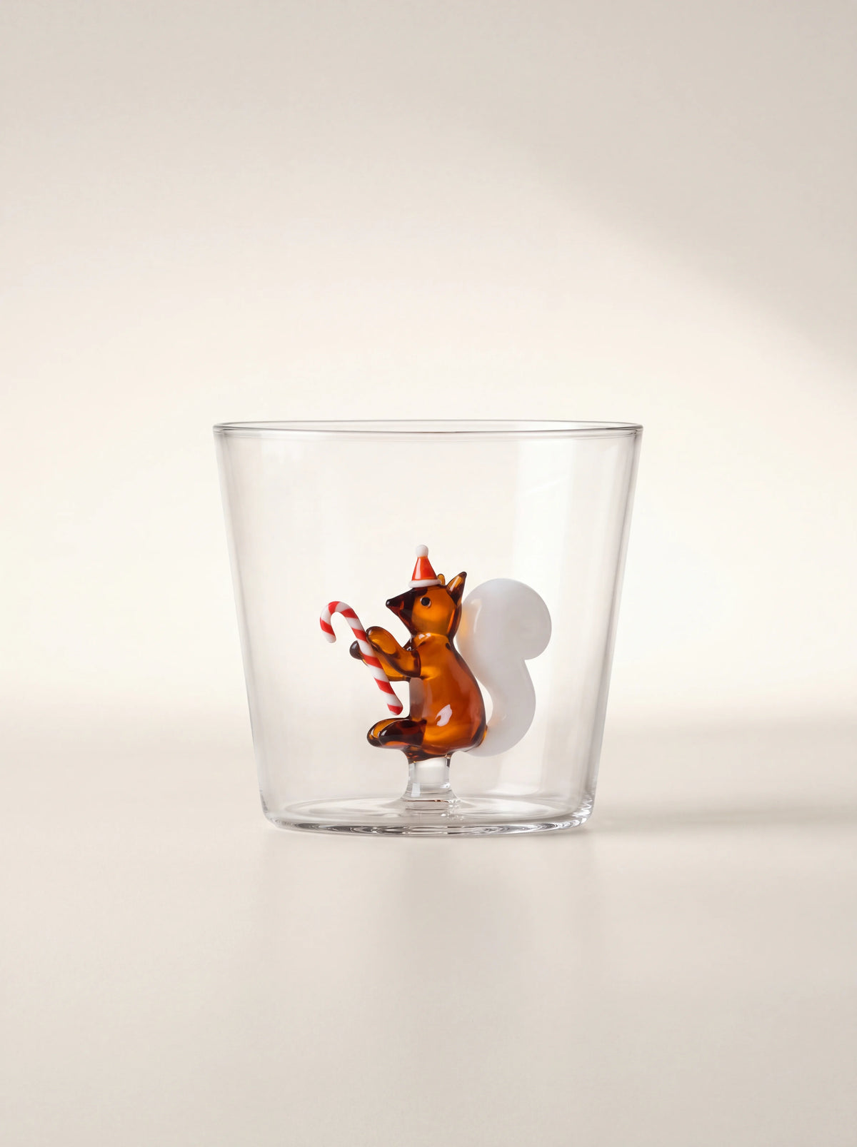 Clear borosilicate glass tumbler featuring an internal amber squirrel with a festive hat and candy cane