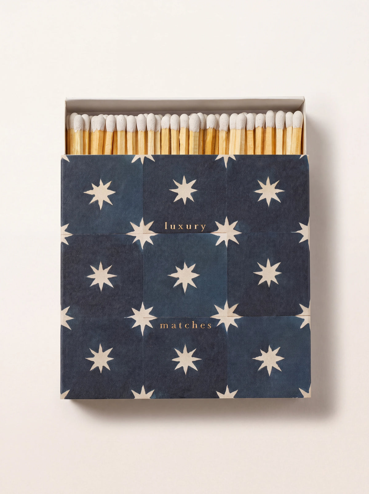 Square matchbox with navy star pattern and text 'luxury matches', open to reveal white-tipped matches