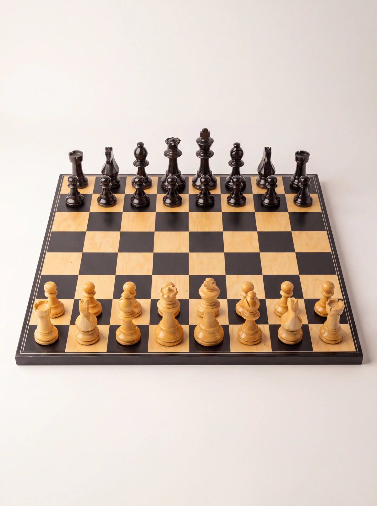 Staunton chess set with black and light wood pieces arranged on a matching square board