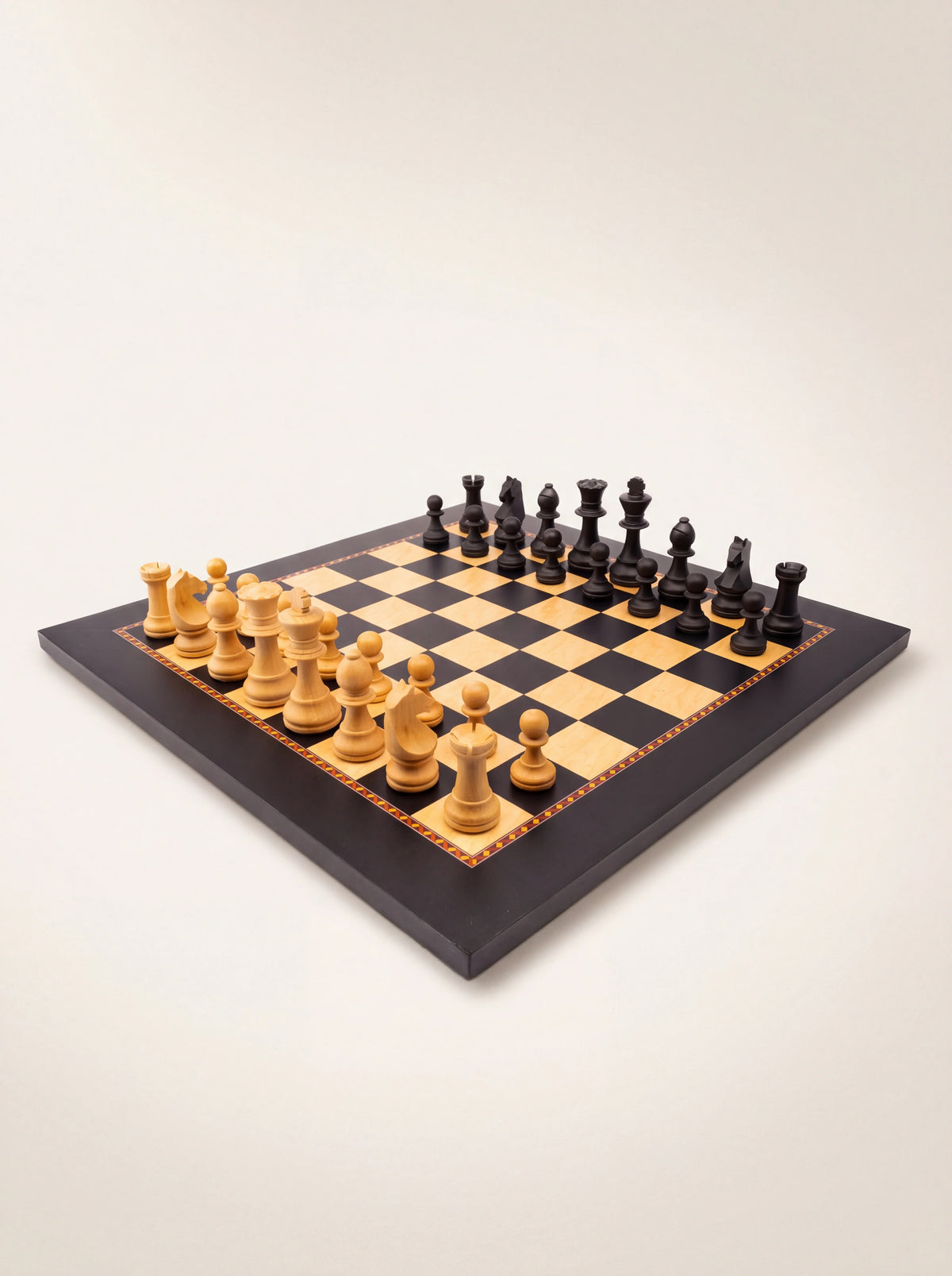 Staunton wooden chess set with light and dark pieces arranged on a chequered board with an inlaid border