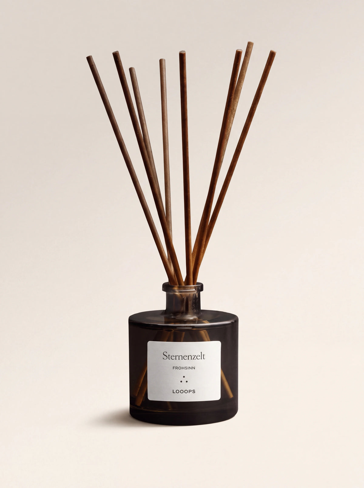 Dark glass reed diffuser with eight paper sticks and a white label reading Sternenzelt