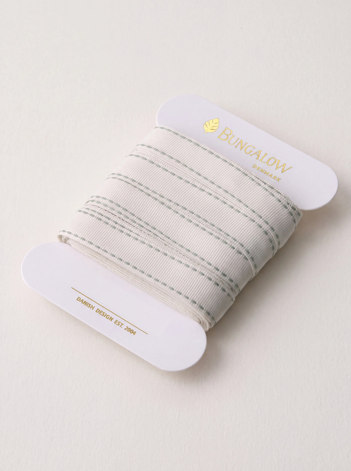 Cream polyester ribbon with ivy green stitched edge detailing, wound around a white card bobbin