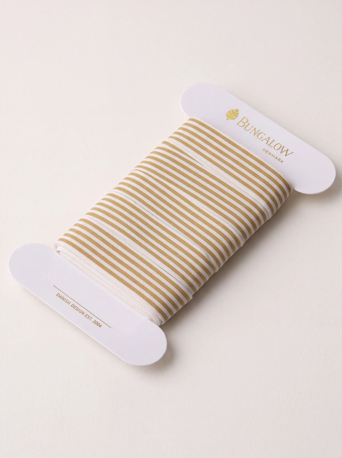 Dijon yellow and white striped ribbon wound on a white cardboard spool
