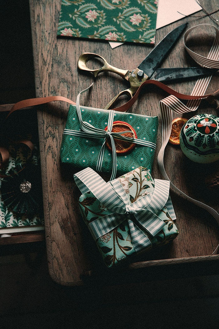 Striped ribbon tied around a small wrapped gift parcel on a wooden table