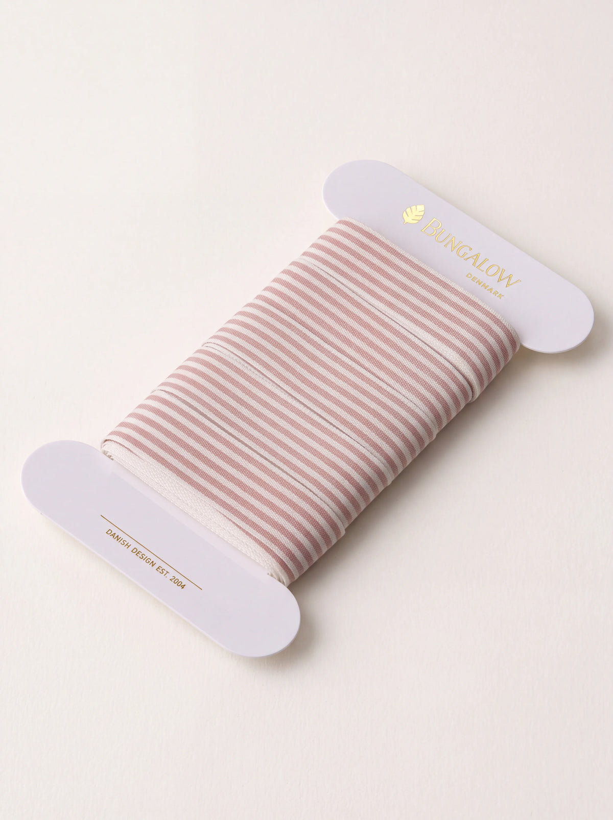Rose and white striped polyester ribbon wound around a white card bobbin