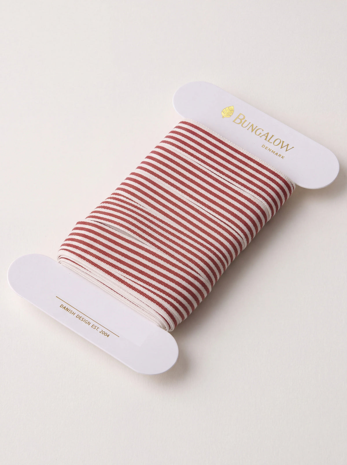 Scarlet and off-white striped ribbon wound around a white card spool