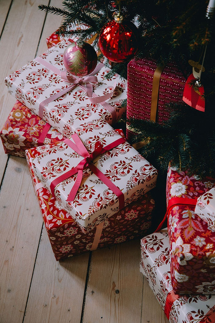 Striped ribbon tied in a bow around a wrapped gift box under a Christmas tree
