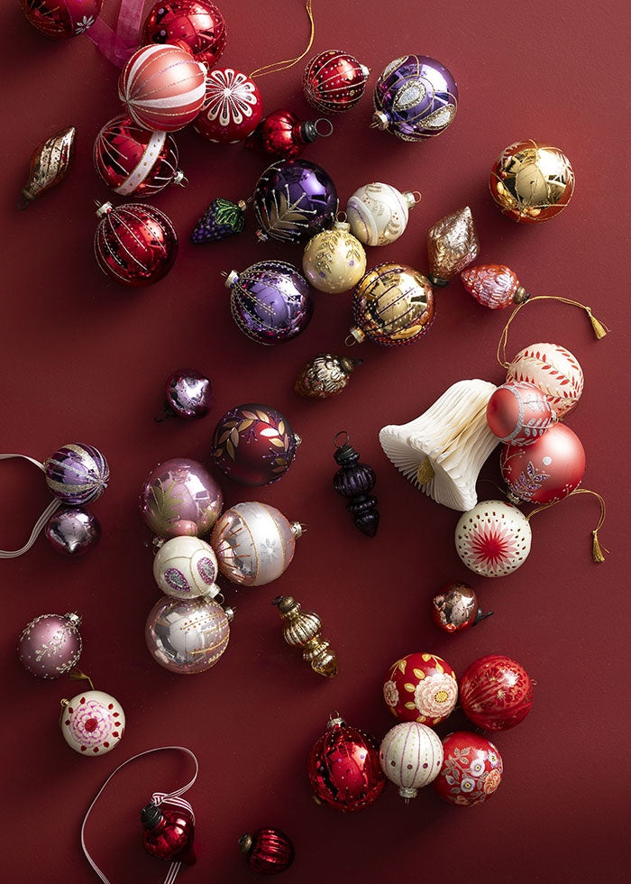 Striped ribbon attached to glass baubles among an arrangement of festive ornaments