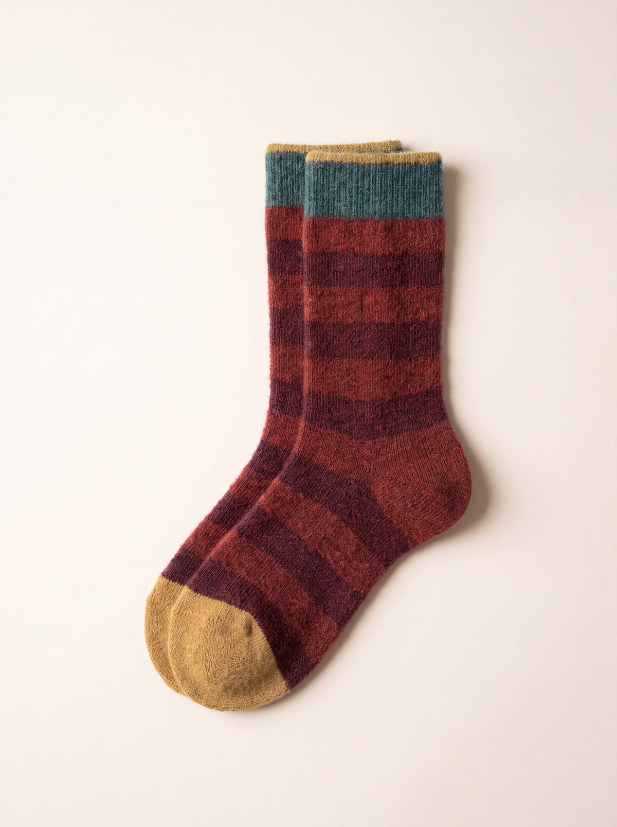 Knitted socks with burgundy and red stripes, a teal ribbed cuff and mustard yellow toes