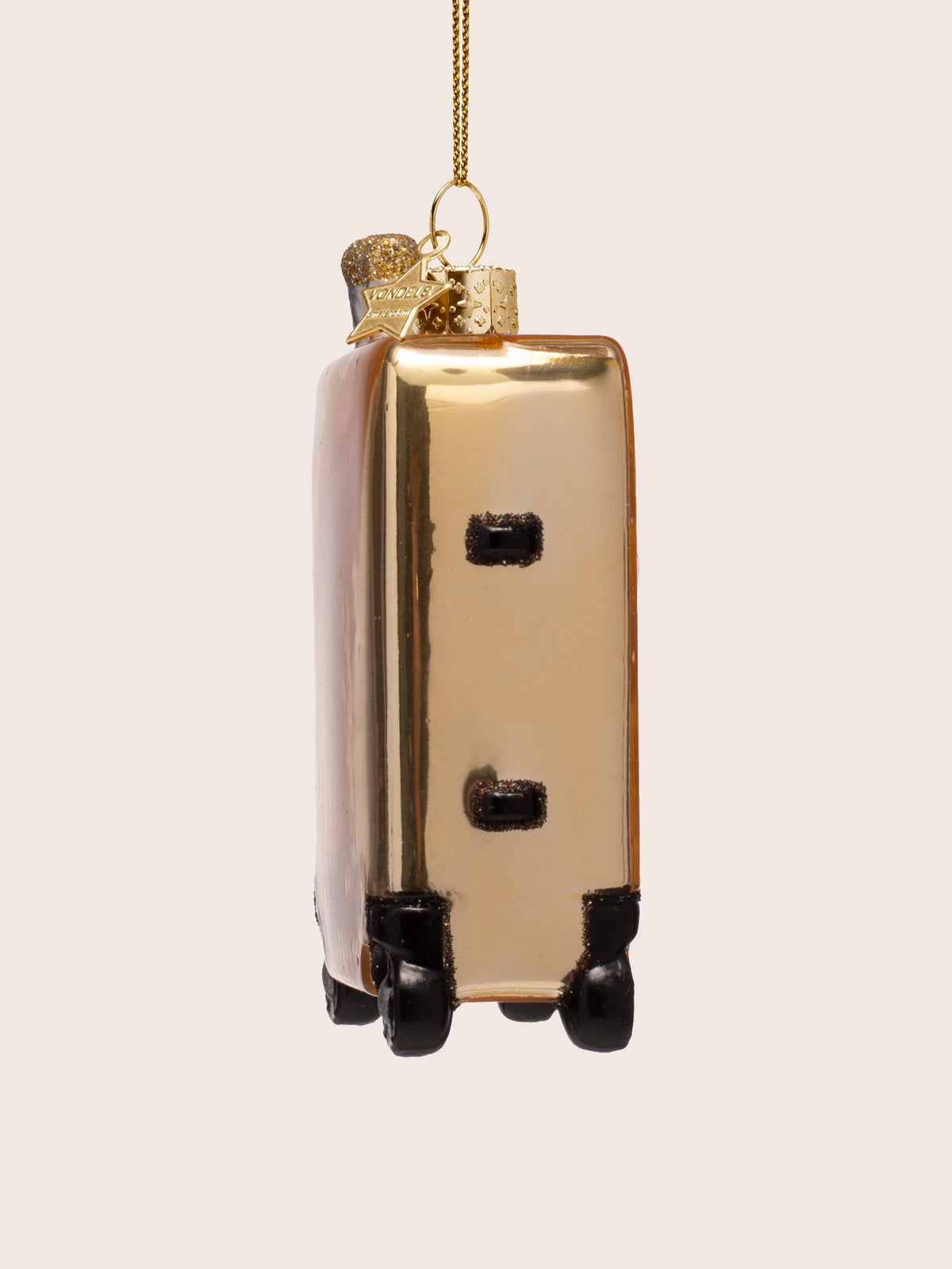 Side view of the gold glass suitcase ornament with black side bumpers and caster wheels