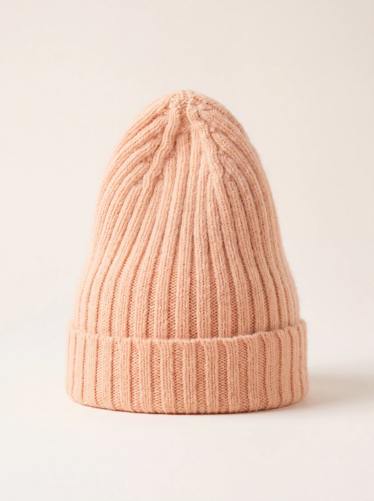 Peach ribbed wool beanie with an elongated crown and a wide turn-up cuff