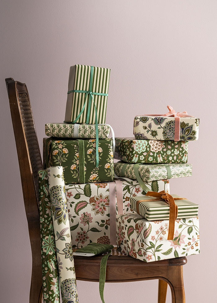 Wrapped gifts and paper rolls stacked on a cane-back chair, showing the floral pattern in use