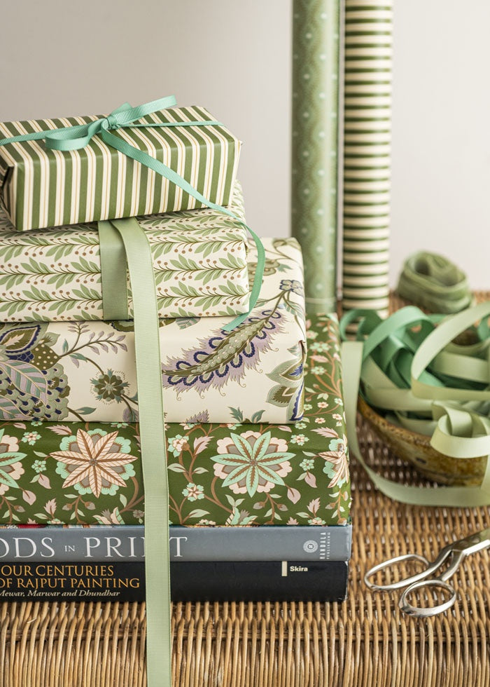 Gift box wrapped in the green floral paper at the base of a gift stack, tied with a ribbon