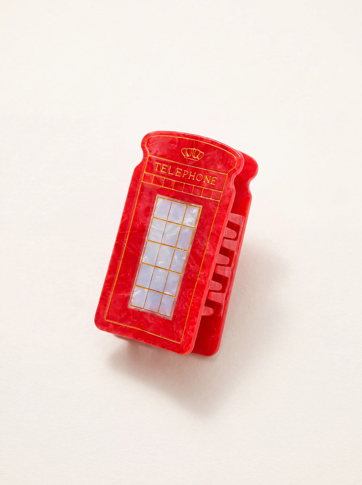 Red telephone box claw clip made of marbled acetate with gold-toned lettering and interlocking teeth