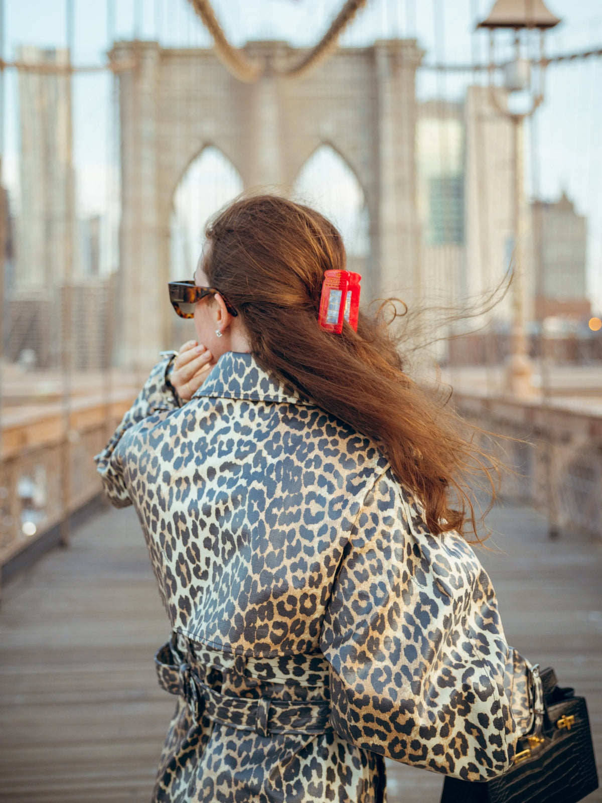Red telephone box claw clip worn in brown hair in a half-up style