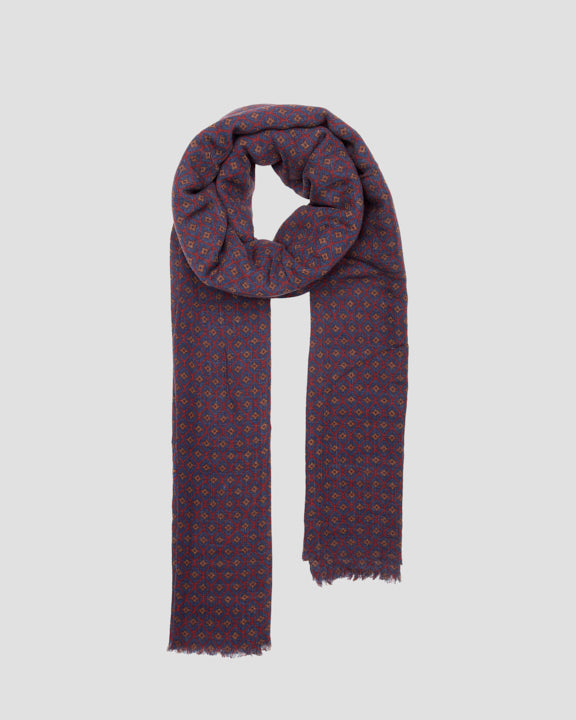 Navy wool scarf with a repeating geometric pattern, styled in a loose loop with fringed ends