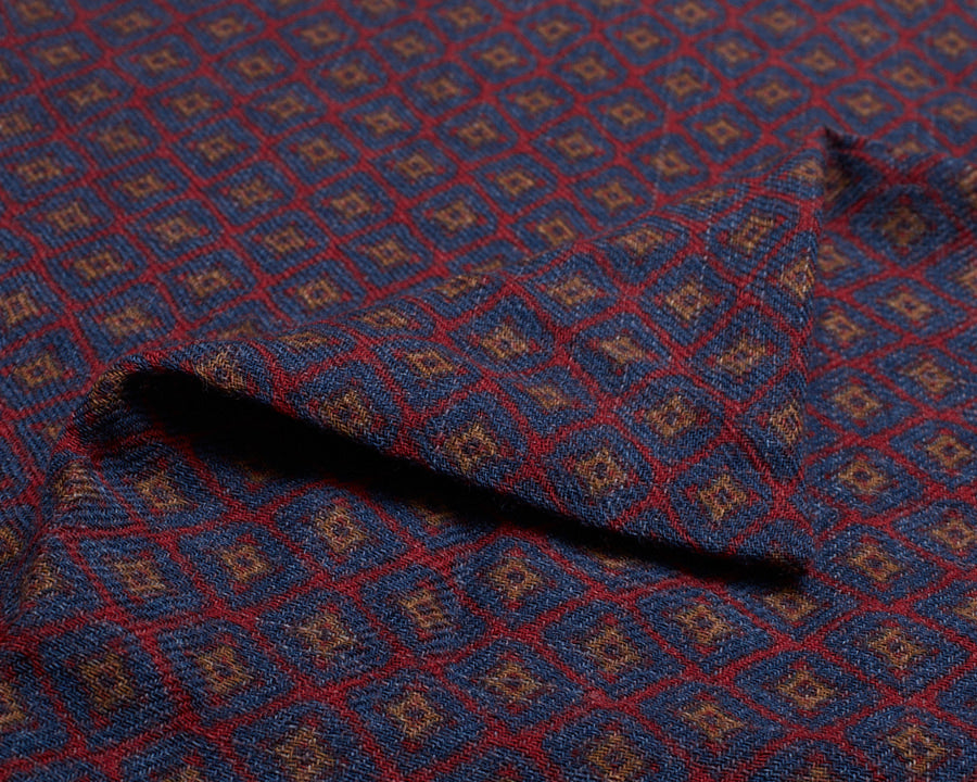 Close-up of the folded wool fabric, showing the woven texture and detailed geometric motif