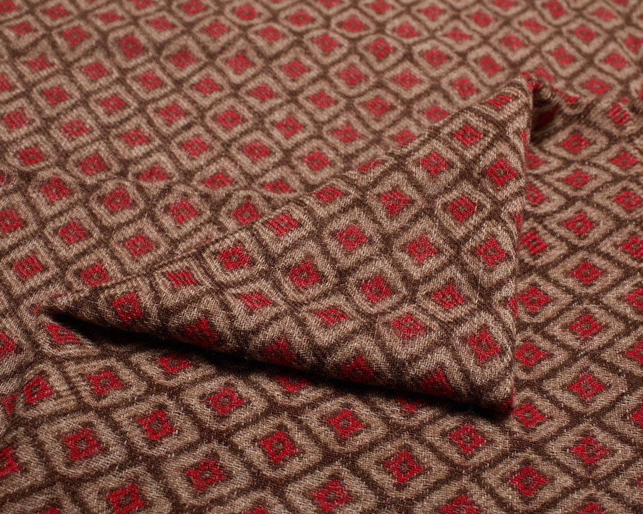 Close-up of the folded wool fabric showing the textured weave and red geometric diamond motif