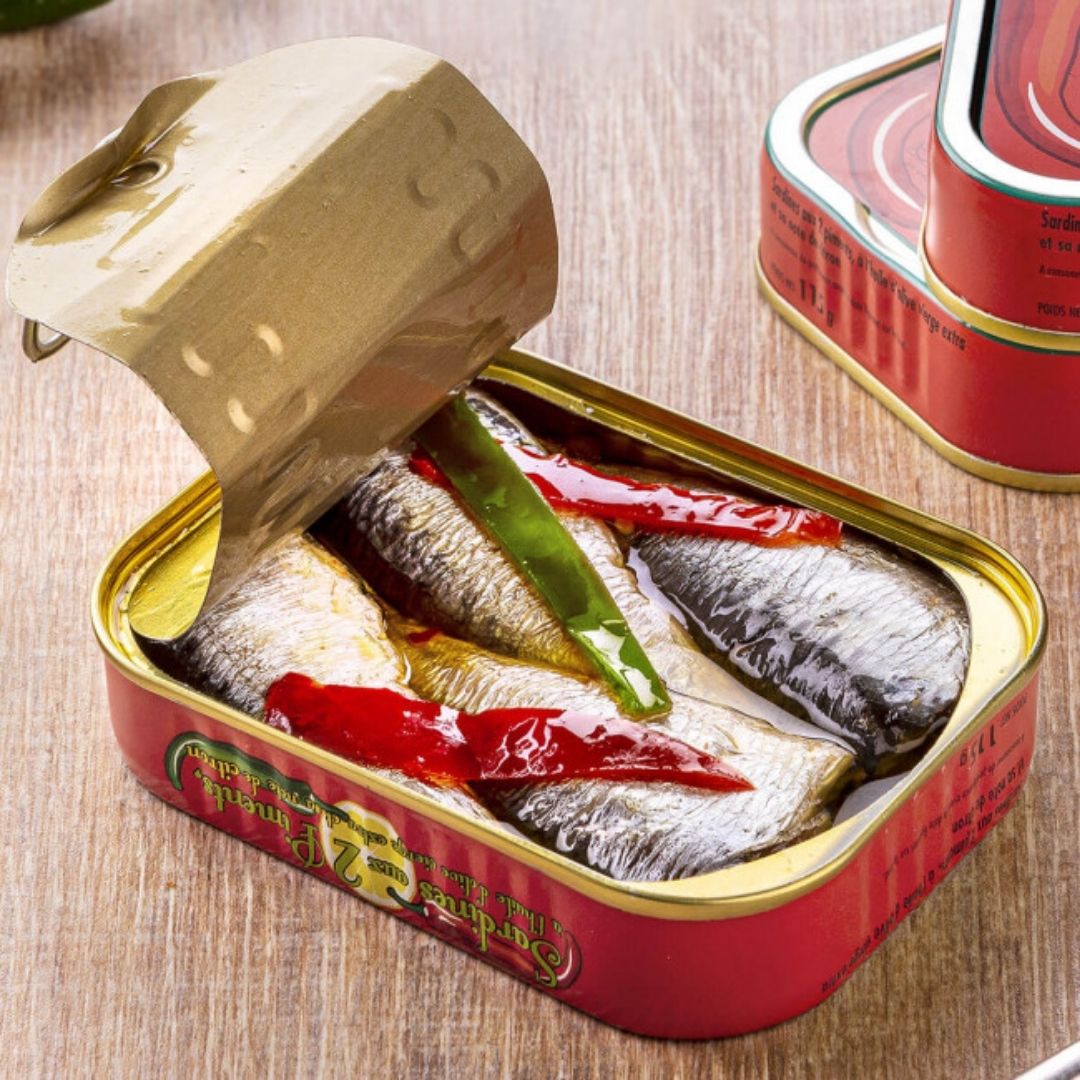 Opened tin of sardines in extra virgin olive oil topped with sliced green and red chillies