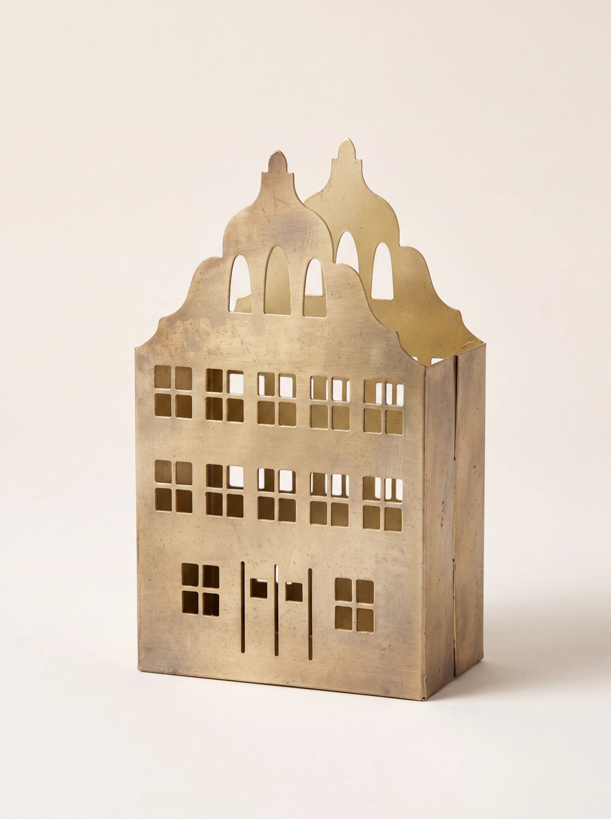 Gold metal townhouse candle holder with a gabled roofline and cut-out windows