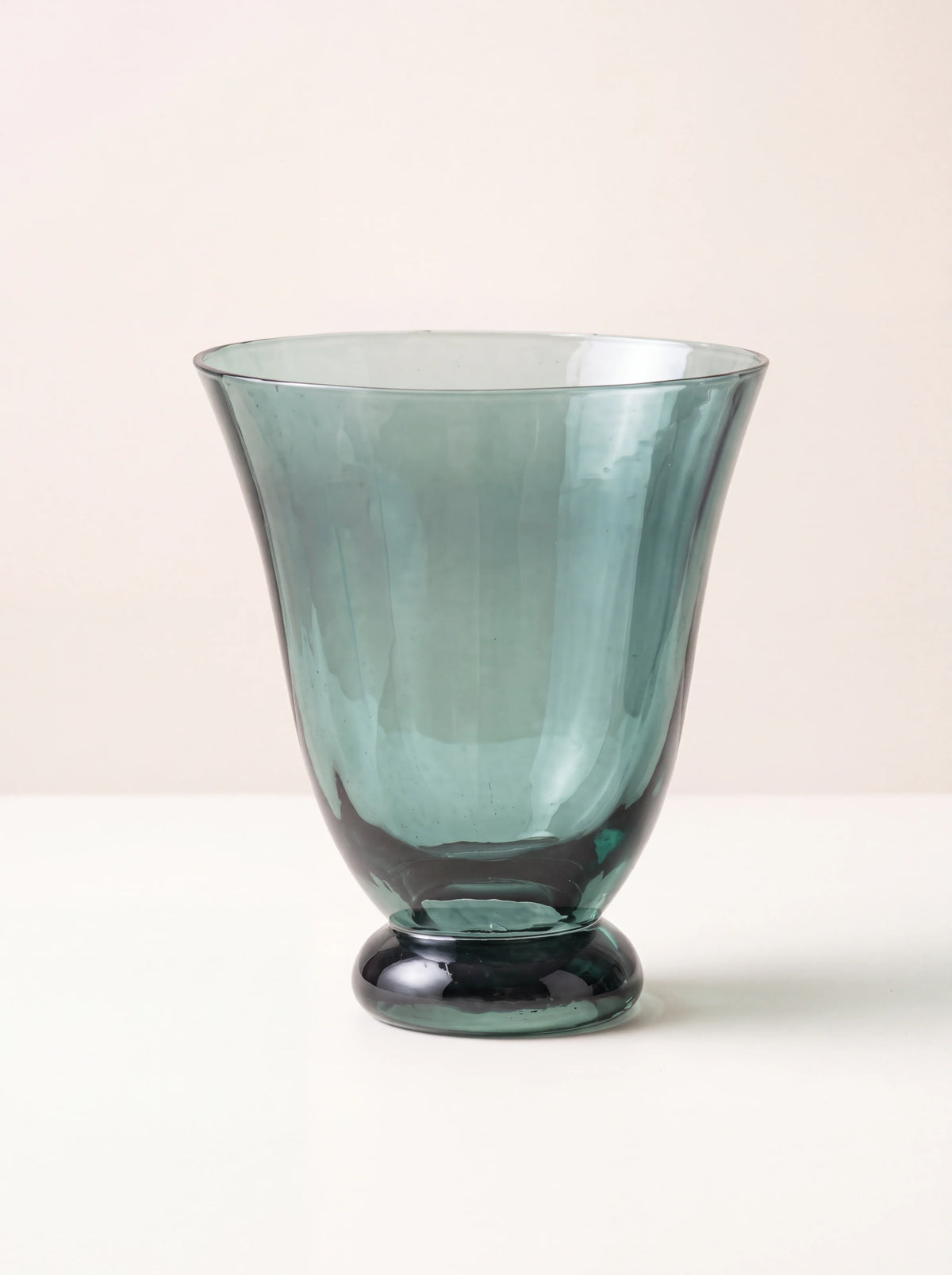 Flared teal glass tumbler with vertical facets and a rounded foot