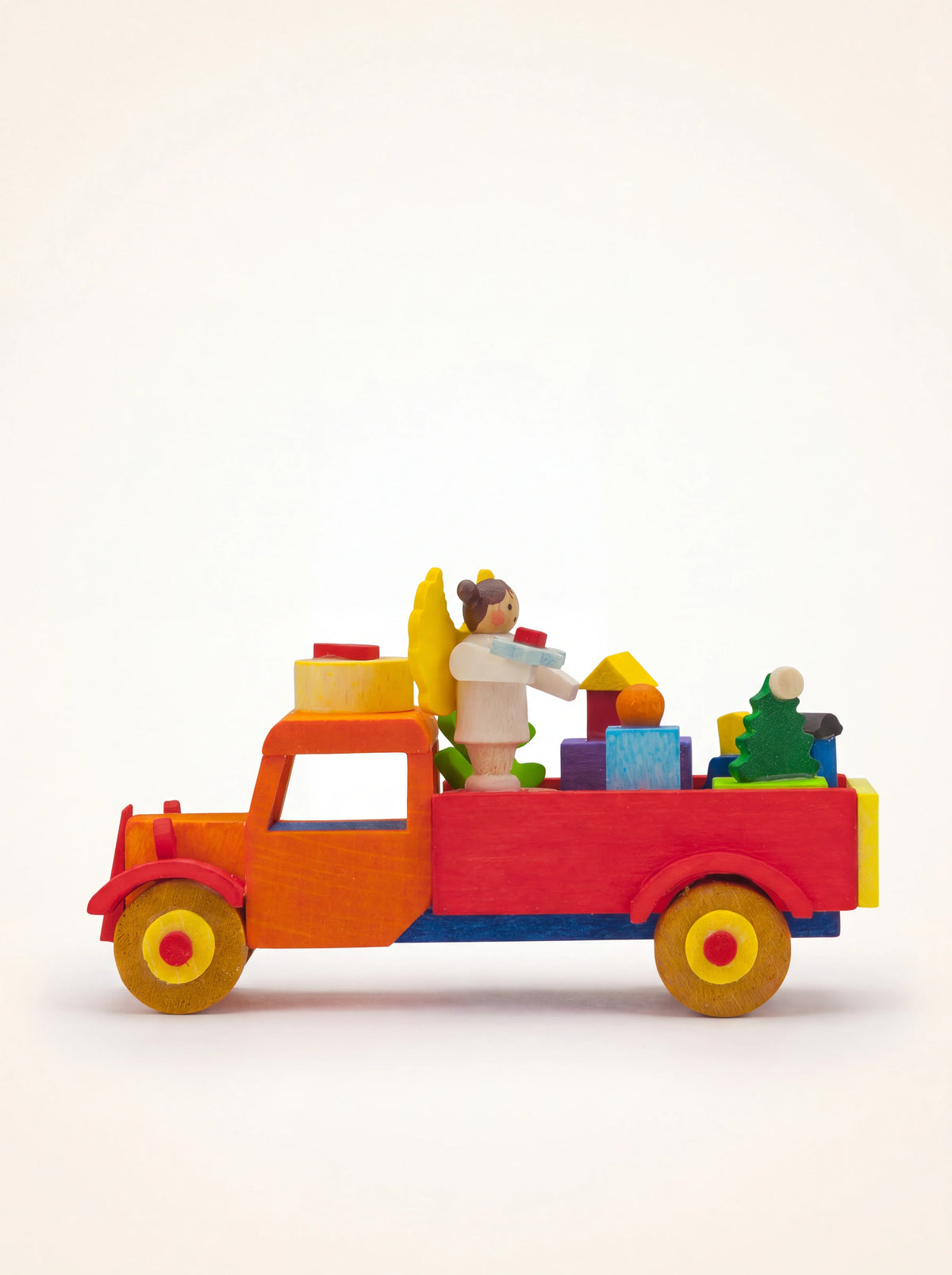 Painted wooden truck ornament in orange and red carrying an angel figurine, miniature tree and colourful gifts