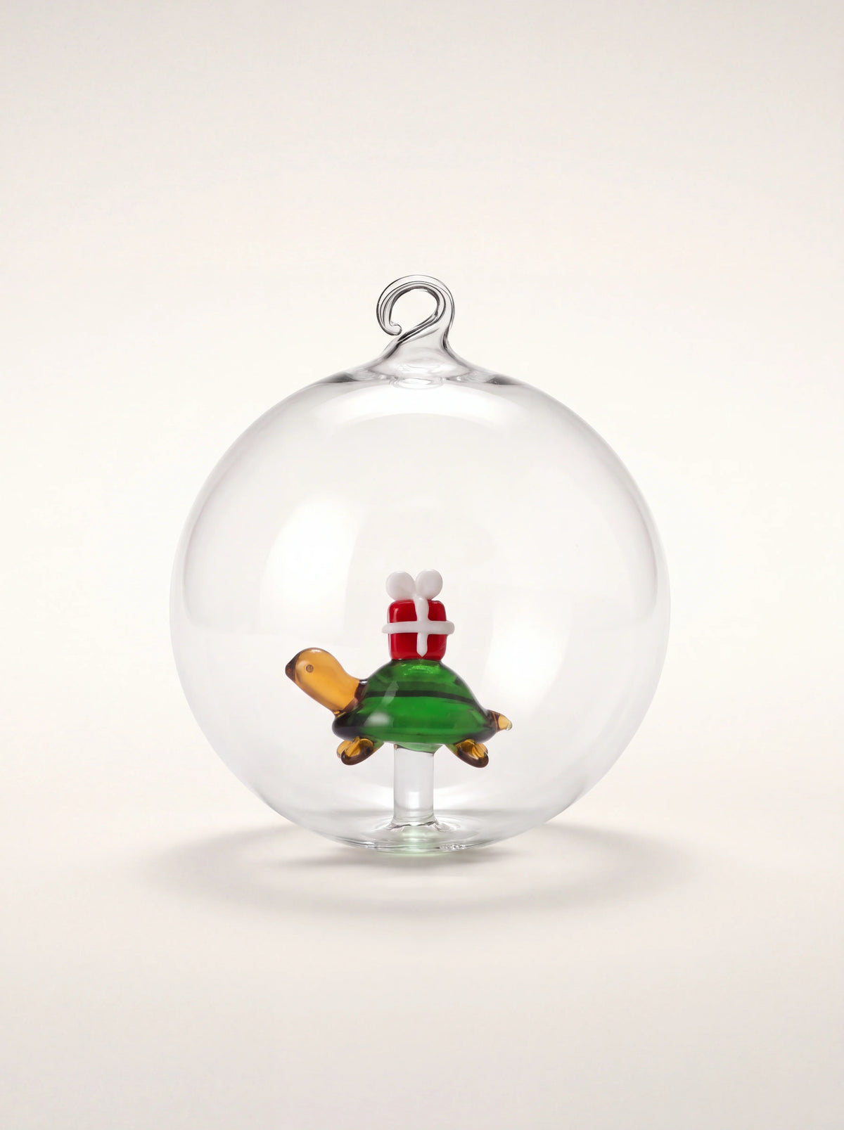 Clear borosilicate glass bauble with an internal lampworked green turtle carrying a red gift box