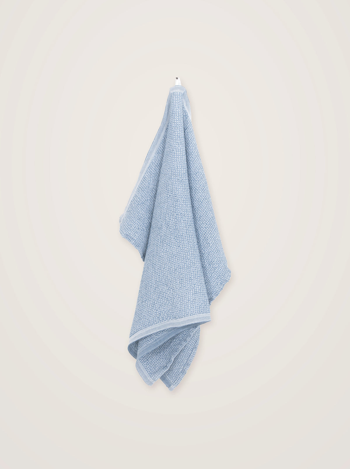 Two-tone blue towel with a textured weave and flat woven border, draped from a hook