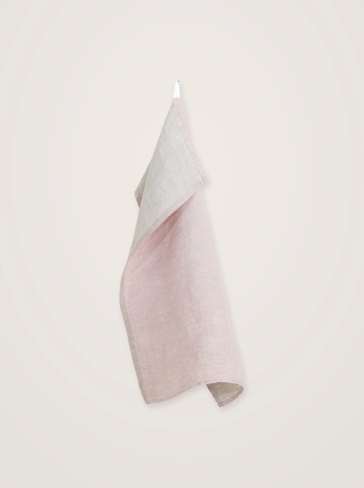 Rose washed linen towel hanging by its loop, with the grey back folded forward