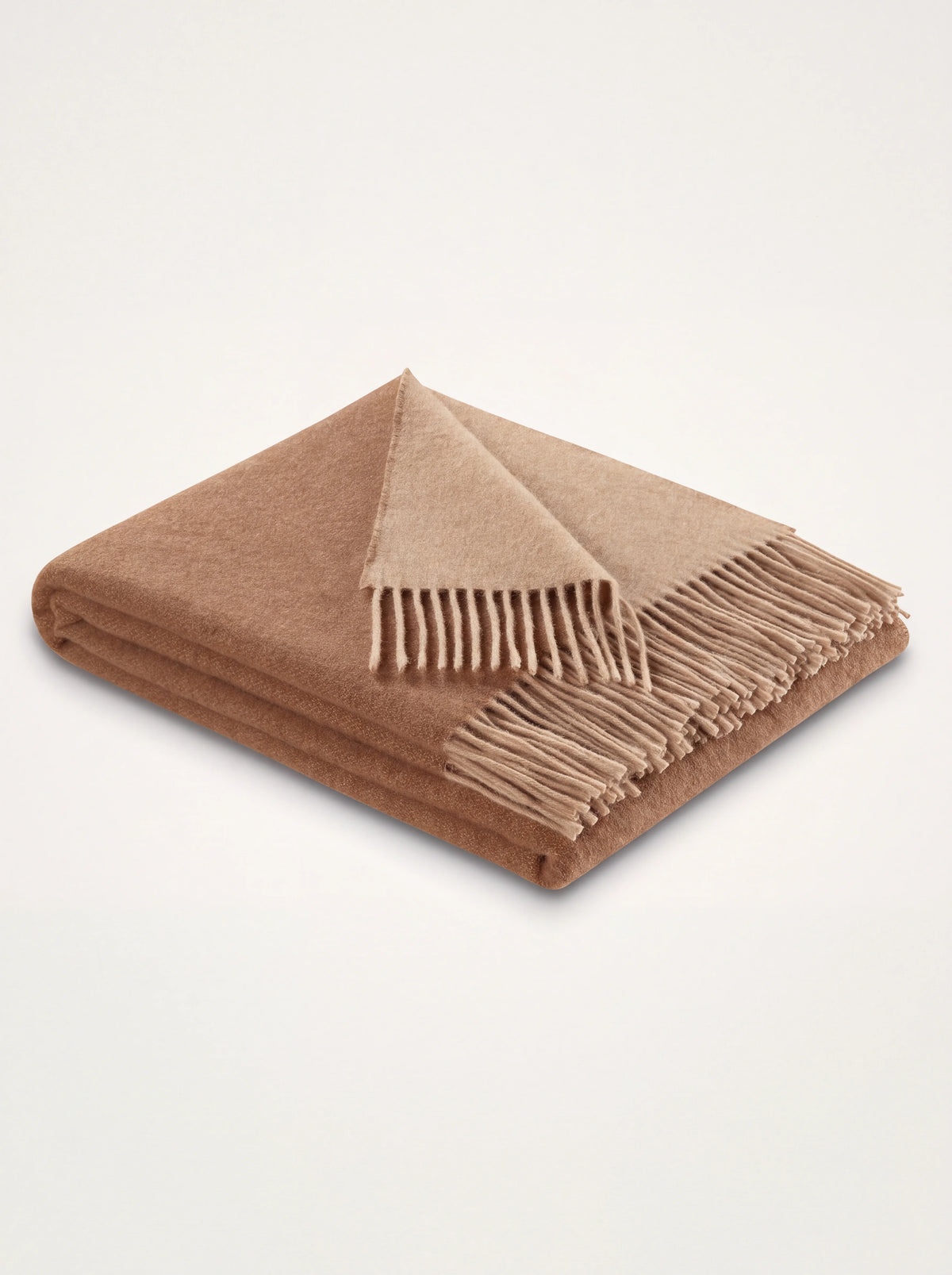 Two-tone wool and cashmere blanket folded to show the camel and beige sides with fringed ends