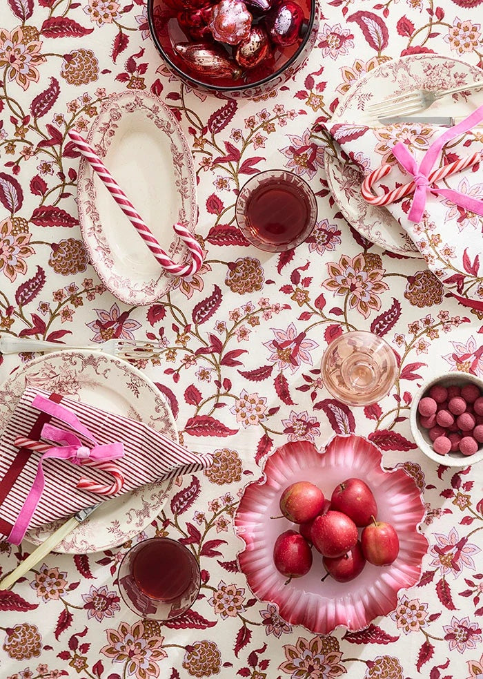 Pink velvet ribbon tied in bows around folded napkins with candy canes on a set table