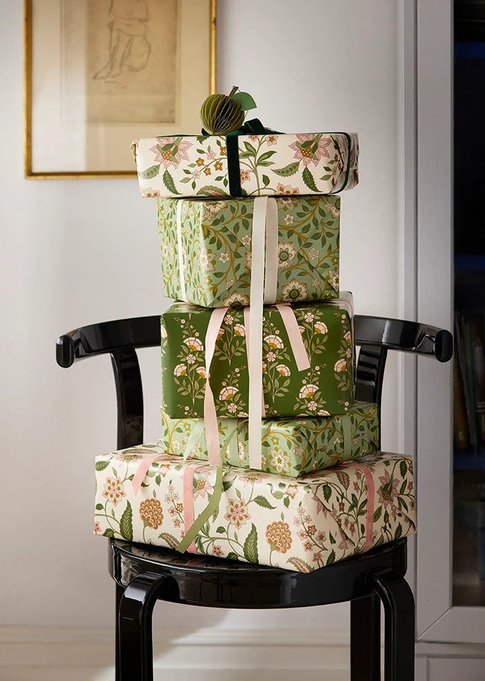 Dark green velvet ribbon tied around the top parcel in a stack of floral-wrapped gifts