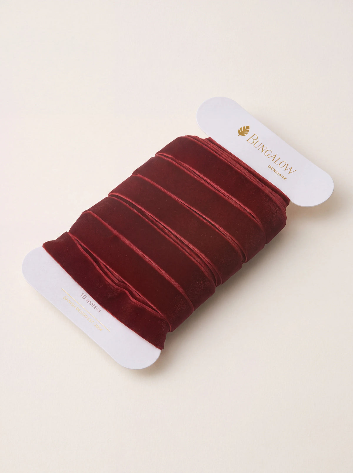 Wine-red velvet ribbon wound on a white card spool labeled 10 meters