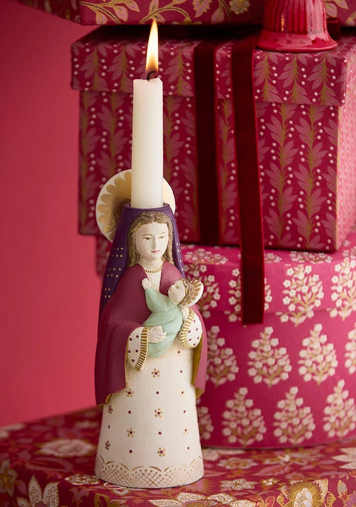 Wine-red velvet ribbon decorating stacked patterned gift boxes behind a candle holder