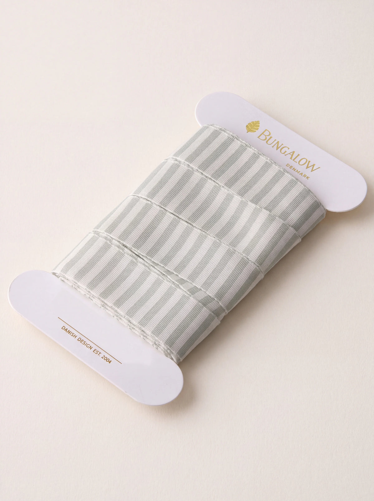 Vertical striped polyester ribbon in ivy green and white, wound around a flat white card spool