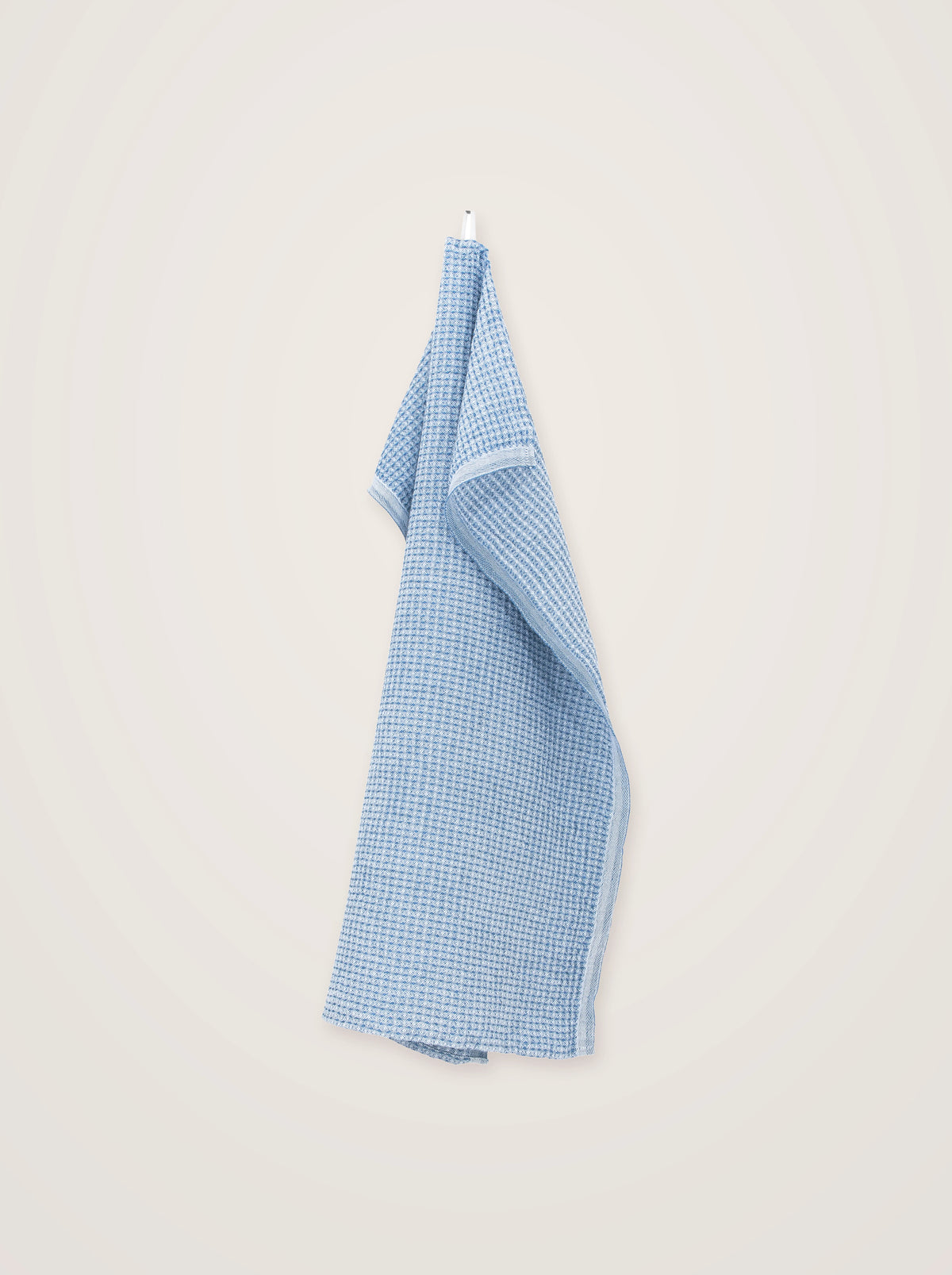 Light blue linen-blend towel in a textured waffle weave, draped vertically showing the hemmed edge