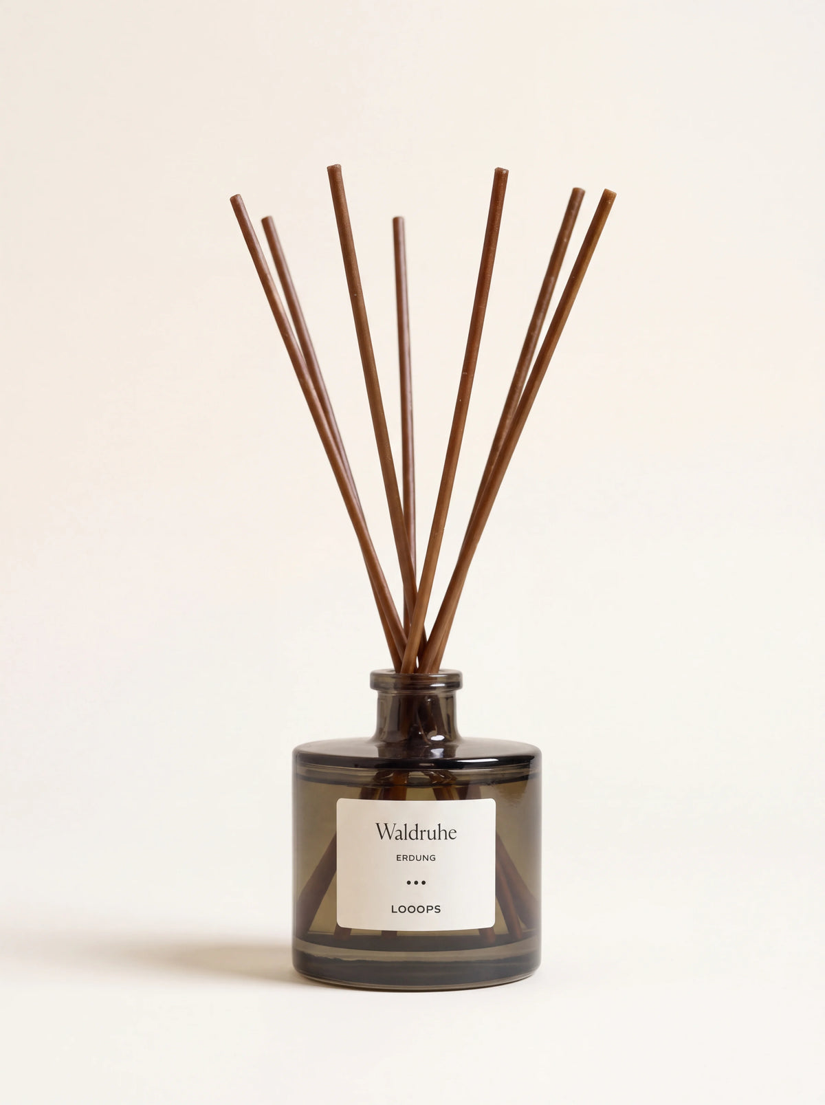 Reed diffuser in a smoky tinted glass flacon with dark paper reeds and a label reading Waldruhe Erdung