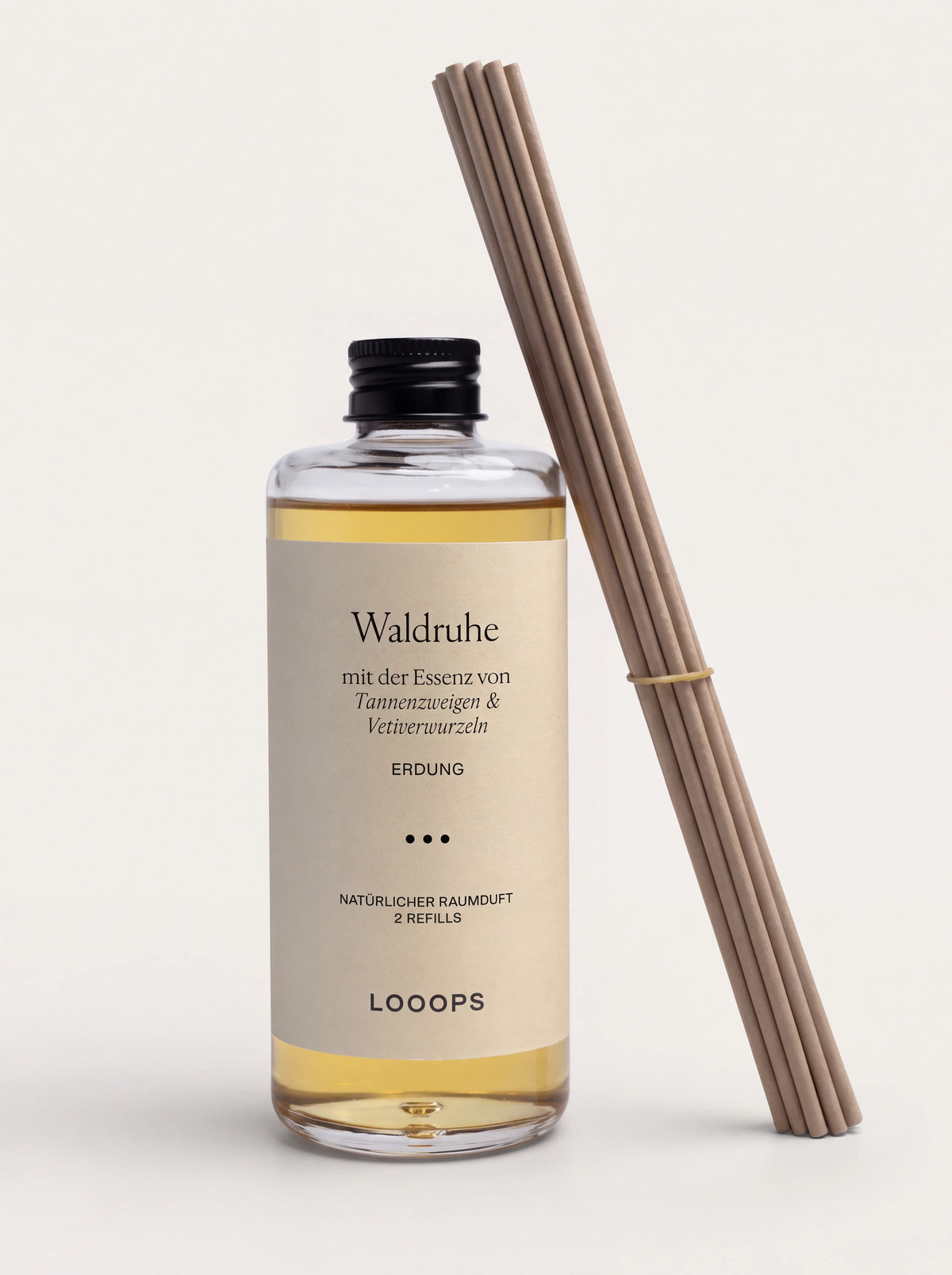 Waldruhe reed diffuser refill in a clear glass bottle with amber liquid, next to a bundle of paper reeds