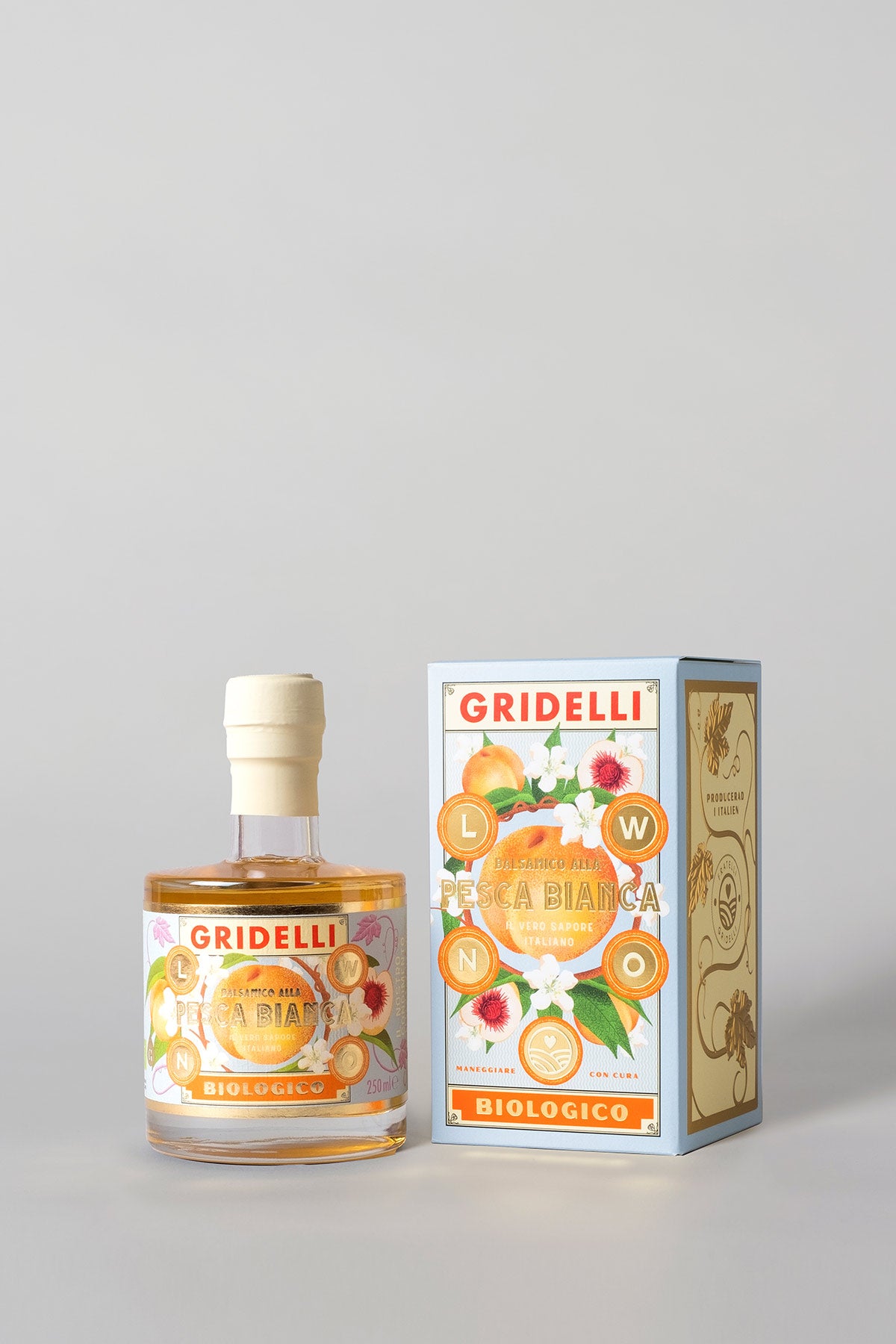 White peach balsamic vinegar bottle next to its matching pale blue illustrated packaging box