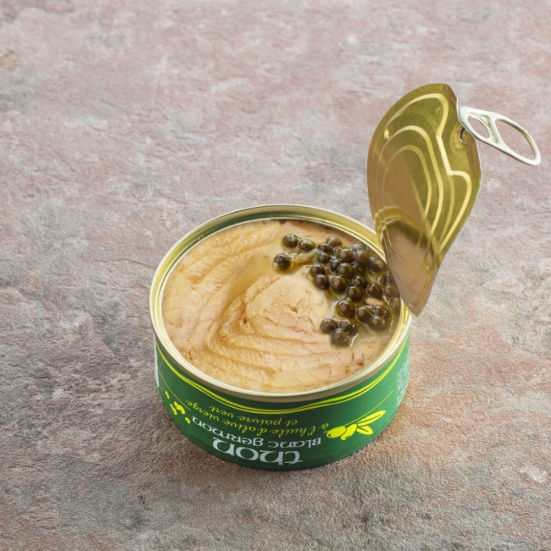 Opened tin with the ring-pull lid peeled back, showing the tuna fillet in oil topped with green peppercorns