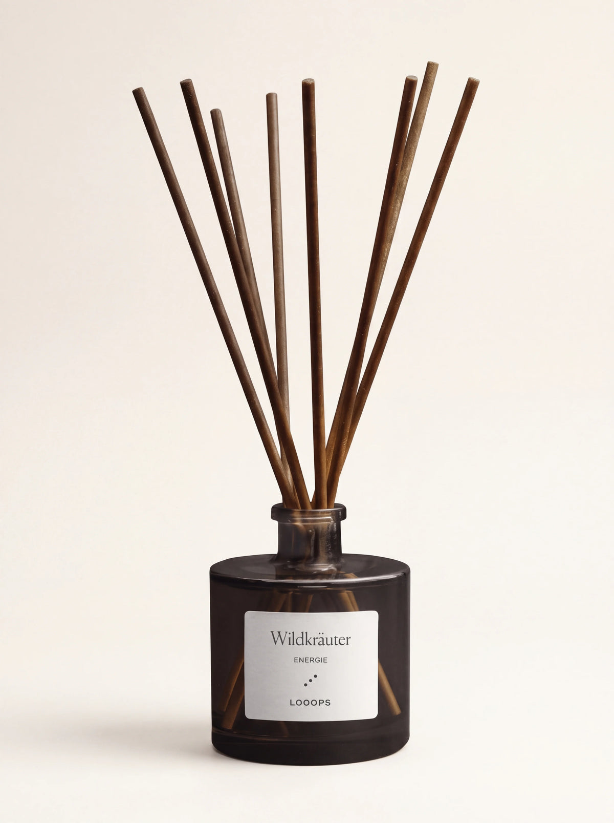 Reed diffuser in a cylindrical dark glass bottle with eight brown paper reeds and a Wildkräuter label