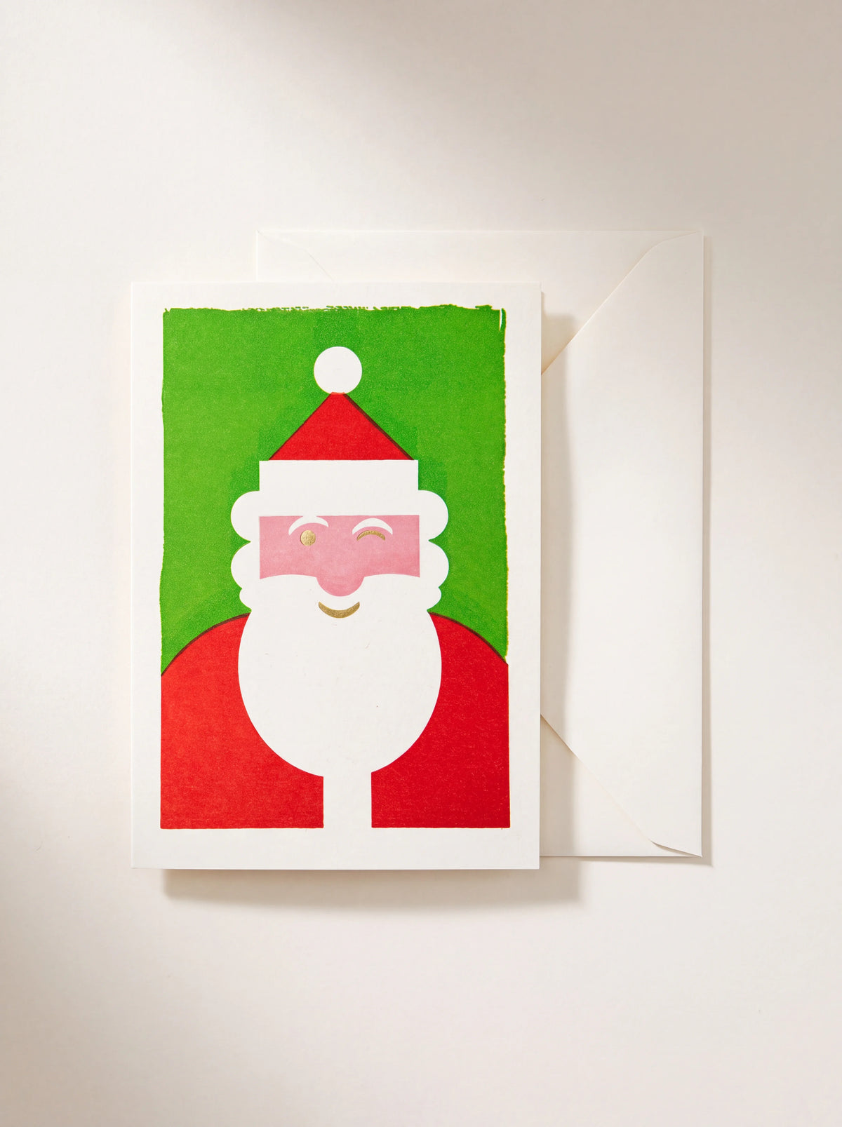 Christmas card featuring an illustrated winking Santa on a bright green background, with a plain envelope