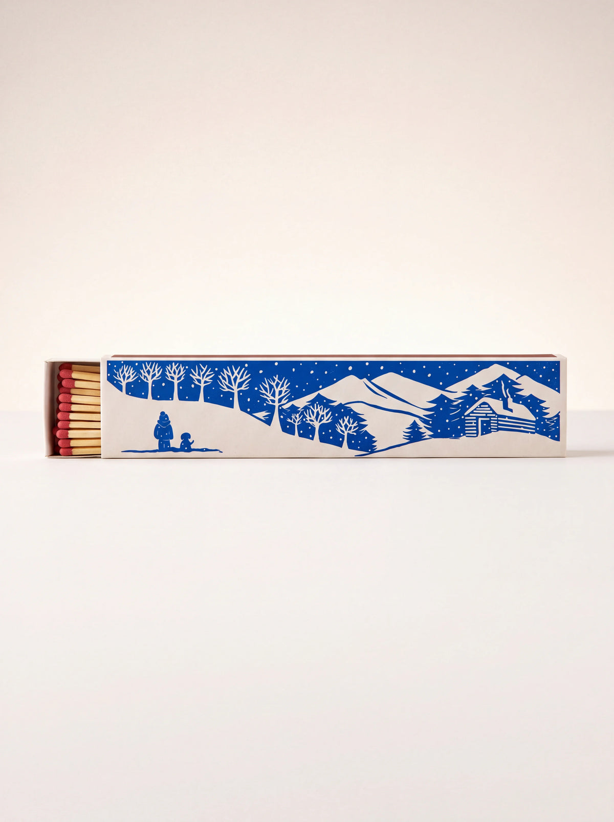 Long matchbox with blue winter mountain landscape illustration, slid open to reveal matches with red tips