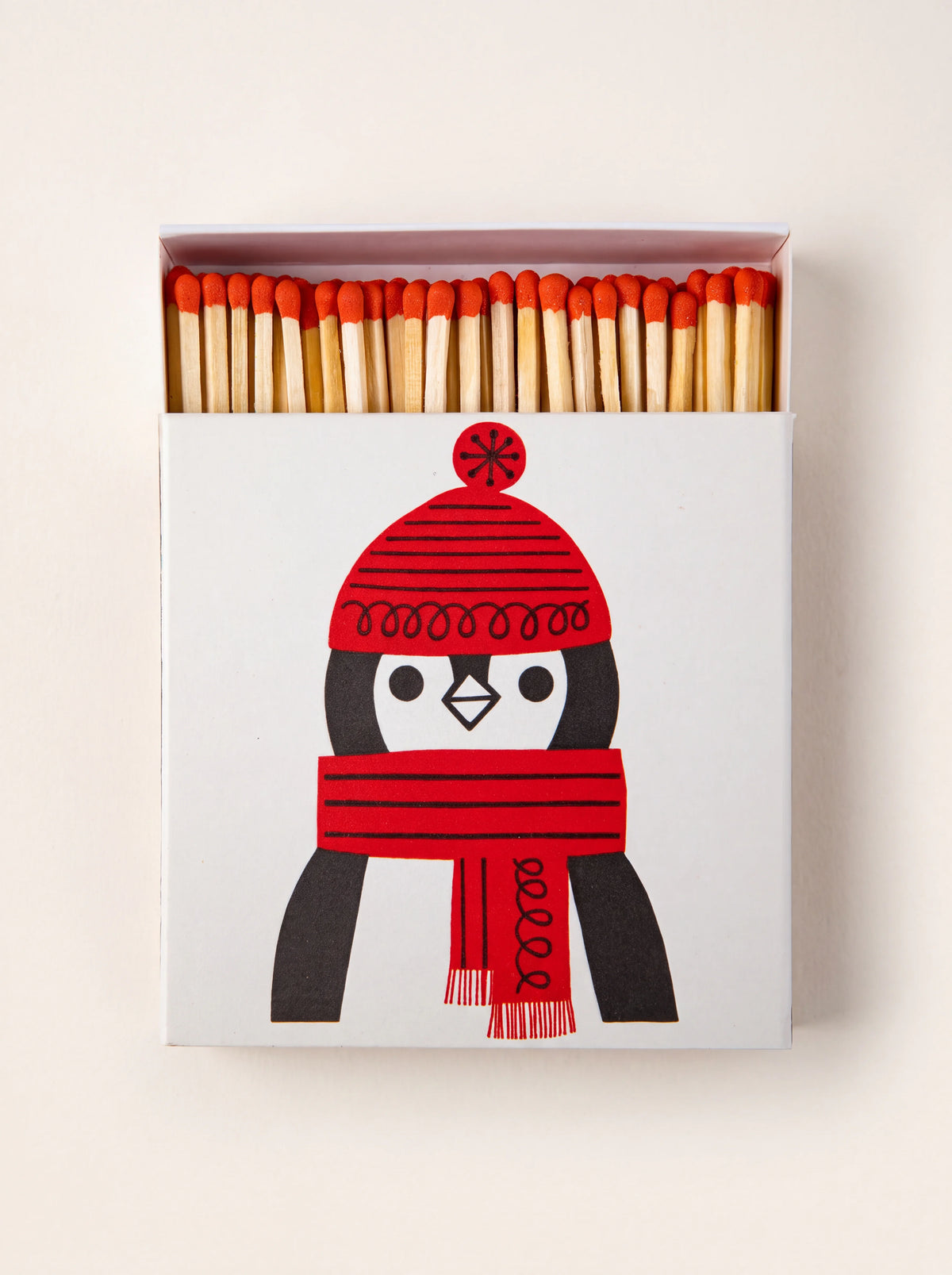 Square matchbox with an illustrated penguin in a red hat and scarf, slid open to reveal red-tipped matches