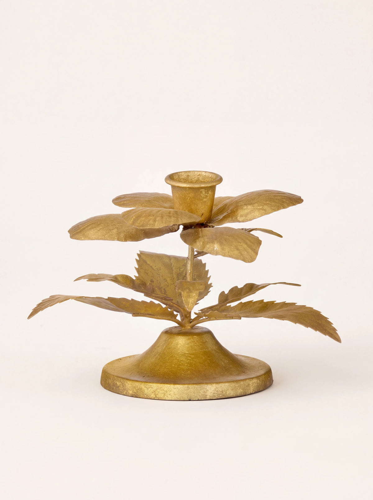 Golden metal candle holder shaped like a winter rose with layered petals, serrated leaves and a flared base