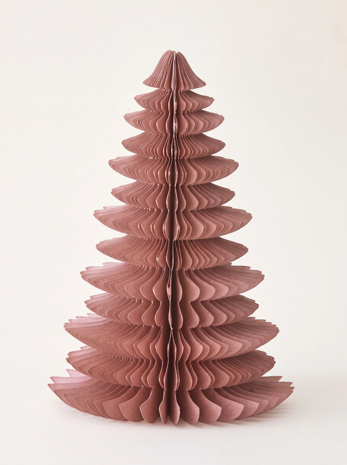 Dusty rose paper tree decoration unfolded in a tiered conical honeycomb structure