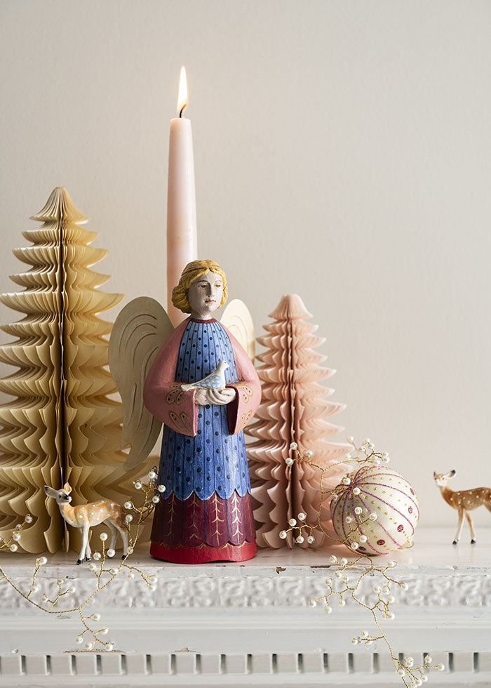 Paper honeycomb tree on a mantelpiece alongside an angel figurine, lit candle and festive ornaments